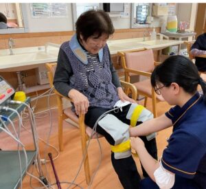 利用者の方の足に器具を装着するKさんの画像