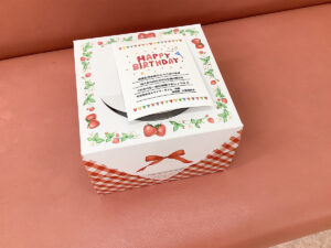 誕生日ケーキの箱の上にメッセージが書かれた画像